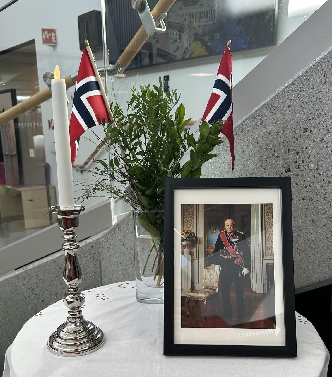 Bord med kvit duk, blomster, norsk flagg og bilde av ein mann i uniform - Klikk for stort bilete
