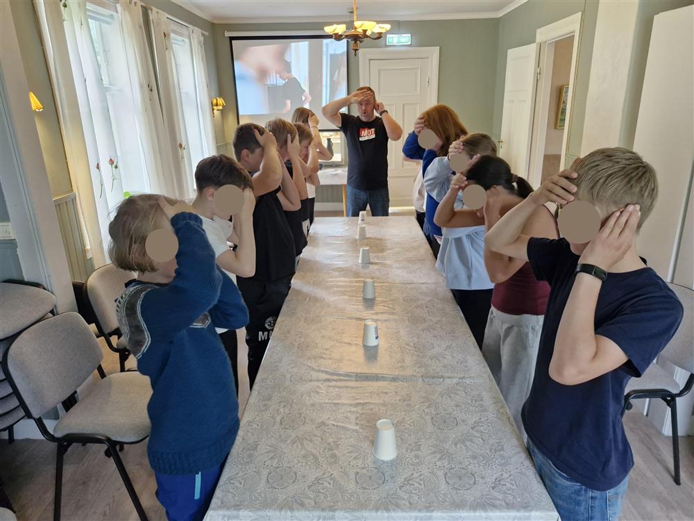 Ungdommar står rundt eit bord og held på med ein aktivitet i lag. - Klikk for stort bilete