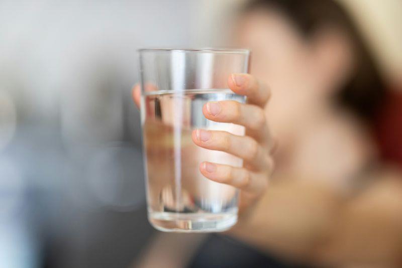 Ein person held fram eit glas med vatn